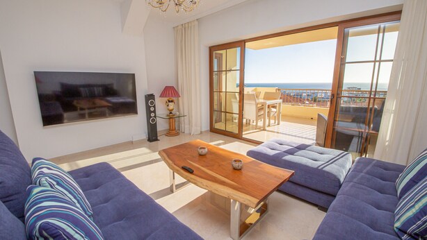 Ein Wohnzimmer mit Fernseher, Couchtisch aus Holz und blauen Sofas.