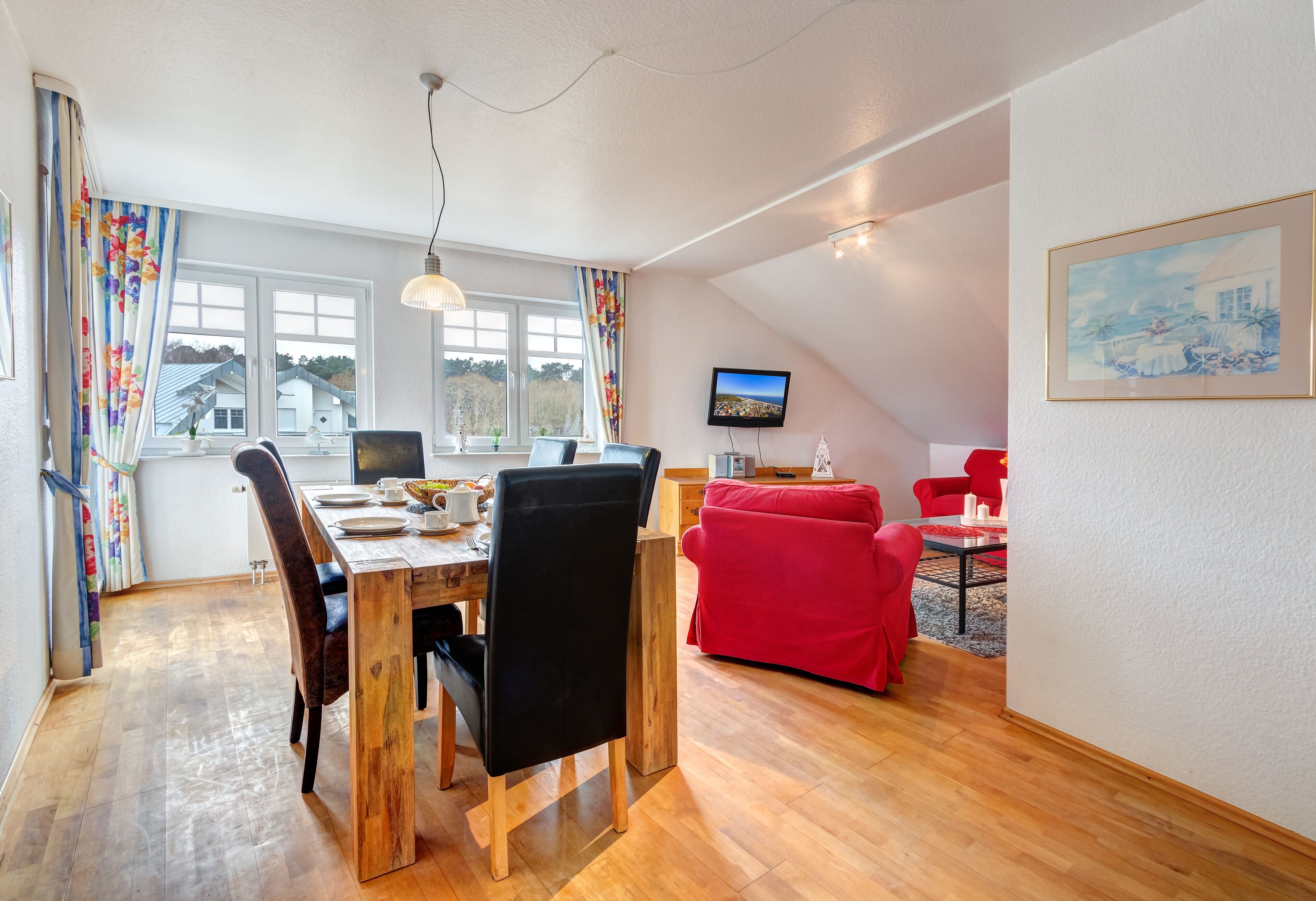 Een eethoek met een houten tafel, stoelen en een rode bank.