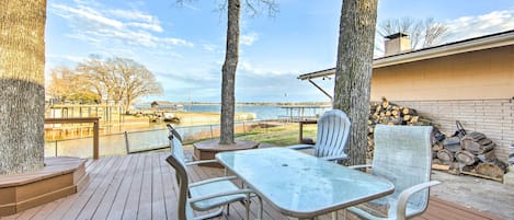 A deck with a table and chairs, overlooking a body of water and a distant shoreline.