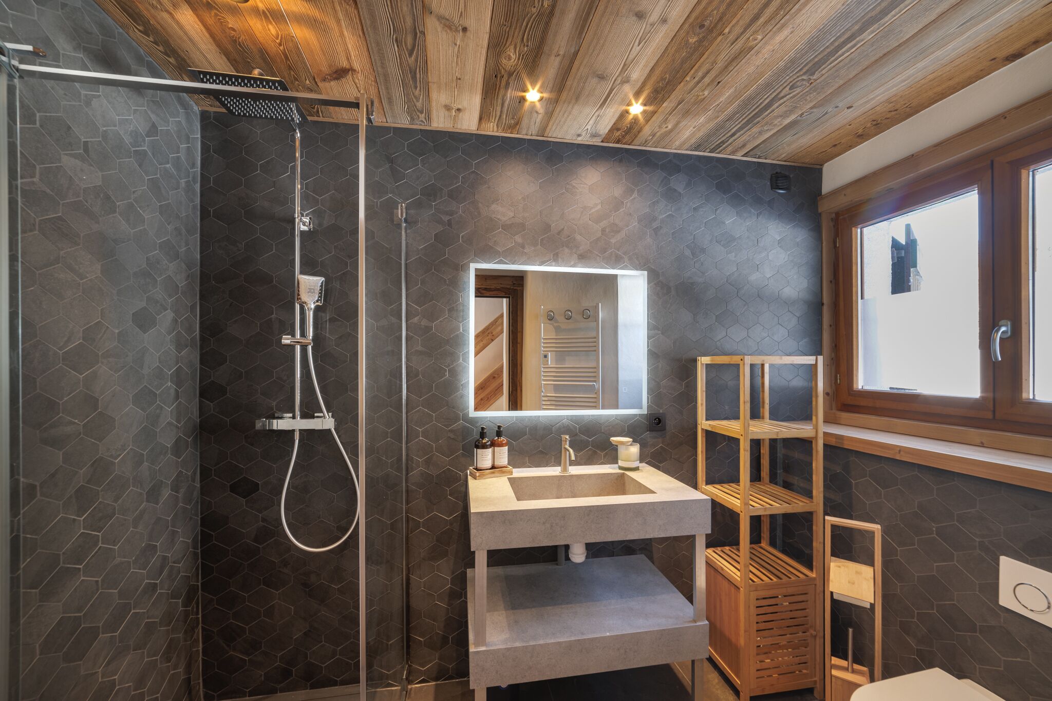 Une salle de bain moderne avec une douche, un meuble-lavabo avec un miroir et des étagères intégrées.