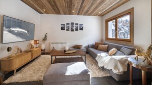 A modern living room with a wooden ceiling, a large flat-screen TV, a sofa, a coffee table, and a fireplace. - Fully renovated La Datcha family chalet, ski room and playroom (Les Contamines-Montjoie)