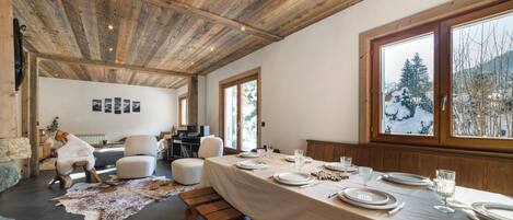 A dining area with a long table set for four, wooden benches, and a rustic ceiling.