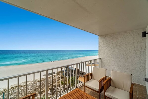 A balcony with a view of the beach and ocean.