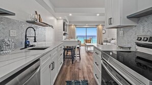 A modern kitchen with a central island, a dining area with a view, and a large oven.