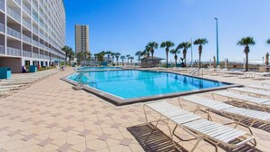 A swimming pool area with lounge chairs and a building in the background.