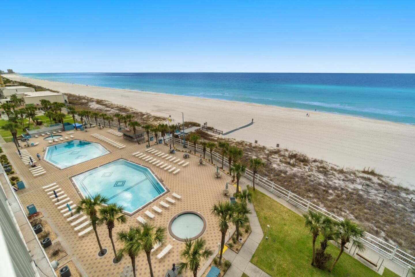 A resort with multiple swimming pools, a beach, and palm trees.