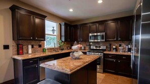 A modern kitchen with dark wood cabinets, stainless steel appliances, and a granite countertop.