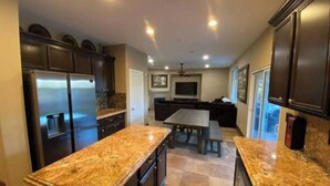 A modern kitchen with granite countertops, dark cabinetry, and a central island.