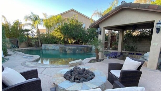 A backyard with a swimming pool, a fire pit, and outdoor furniture.