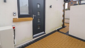 A modern exterior with a dark-colored door, a small window, and a white wall.