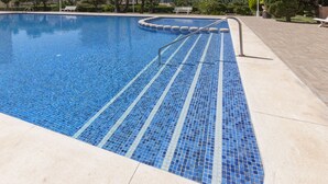 En swimmingpool med blå mosaikfliser og en metalstige.
