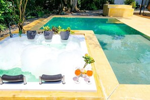 Een whirlpool met drie lounge stoelen en plantenpotten.