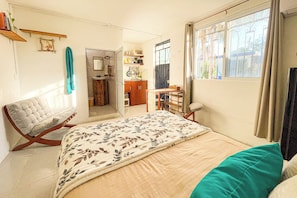 Ein Schlafzimmer mit einem Bett, einem Sessel, einem Schreibtisch und einem Fenster.