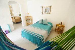A bedroom with a bed, bedside table, and a view of a living area. - Nido Bacalar (Bacalar)