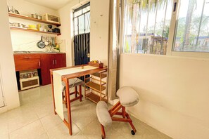 A kitchen with wooden cabinets, a countertop, a sink, and a window with a view of greenery. - Nido Bacalar (Bacalar)