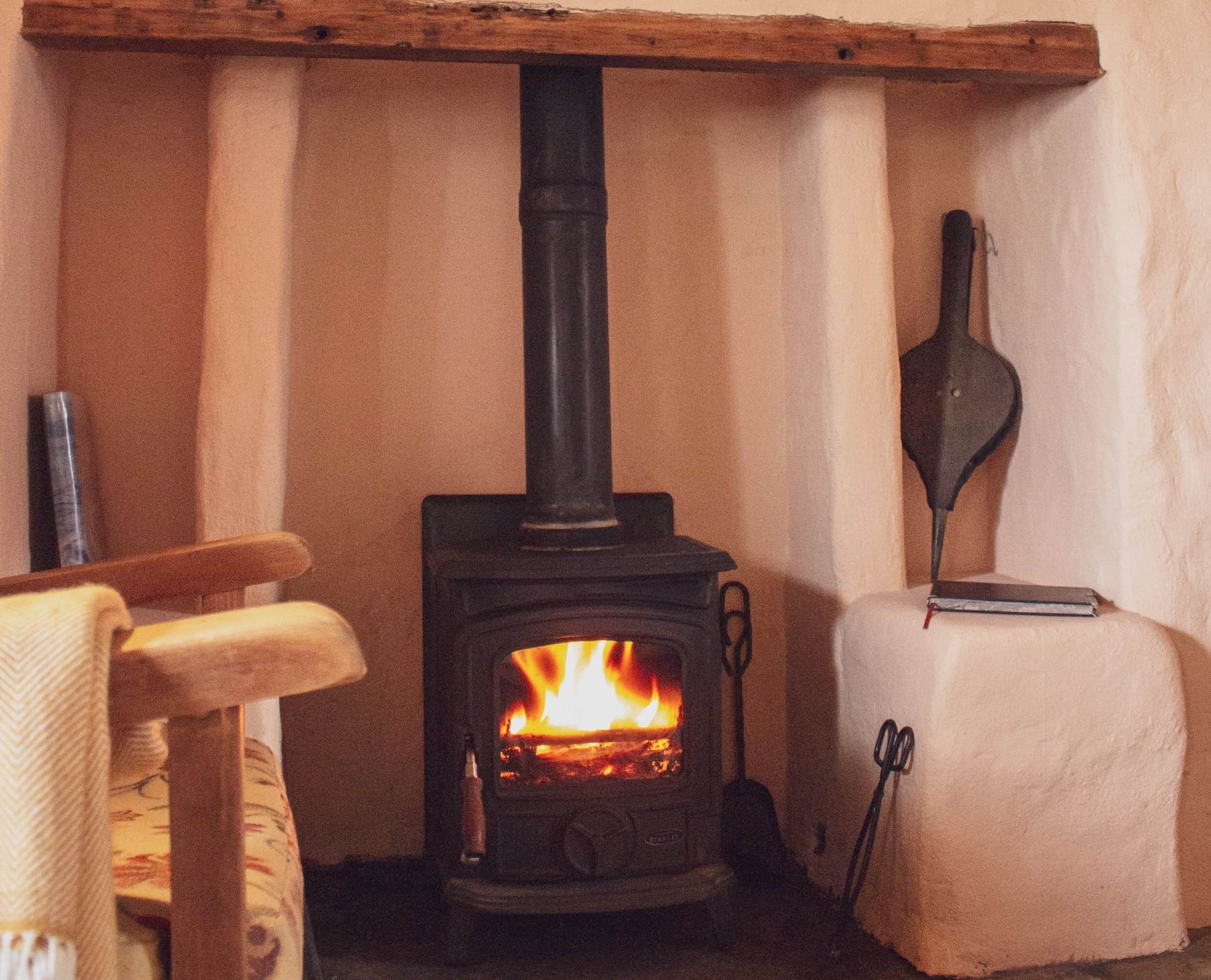 A wood-burning stove with a visible fire, a chair, and a small table with a candle.