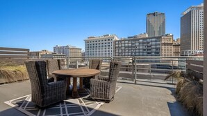 A rooftop terrace with wicker furniture and a city view. - Bourbon Street Bliss (New Orleans)
