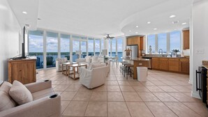 A spacious living area with a kitchen, large windows, and a balcony overlooking the sea. - Stunning Lagoon Front Views | Pool | Fishing Pier & Boat Slips (Gulf Shores)
