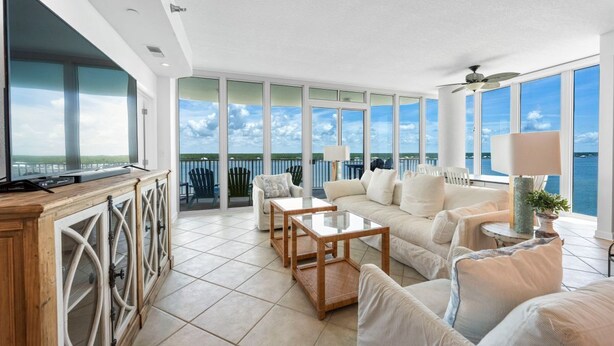 A spacious living area with a large TV, comfortable seating, and a balcony with a view of the sea. - Stunning Lagoon Front Views | Pool | Fishing Pier & Boat Slips (Gulf Shores)