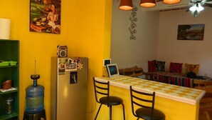 Una cocina con barra, refrigerador, dispensador de agua y mesa de comedor con sillas.