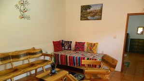 Una habitación acogedora con un banco de madera, una mesita y una cama con ropa de cama colorida.