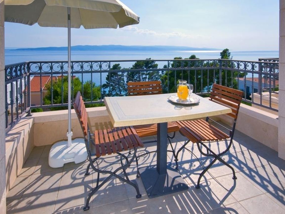 Ein Balkon mit Tisch, Stühlen und einem Getränk.