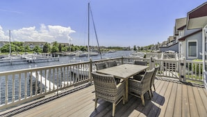 A wooden deck with a table and chairs overlooking a marina with boats. - HV Marina Condo with Boat Slip (Manistee)