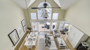 A spacious loft with a high ceiling, a dining area, a sofa, and a view of the water outside. - HV Marina Condo with Boat Slip (Manistee)