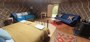 Ein gemütliches Interieur einer Jurte mit Bett, Sofa und einem kleinen Tisch.