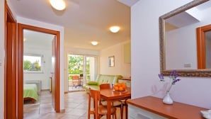 Una habitación con comedor, cocina con gabinete blanco, espejo y ventana.