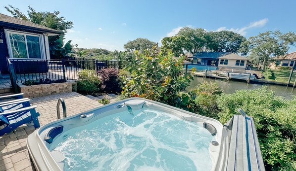 A hot tub on a patio with a view of a canal and buildings in the background. - Dog friendly summer escape: Waterfront, Game Room, Hot Tub (Palm Coast)