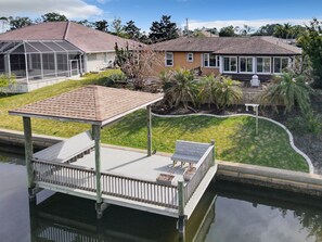 A residential area with a dock extending into a body of water, surrounded by houses and greenery. - Dog friendly summer escape: Waterfront, Game Room, Hot Tub (Palm Coast)