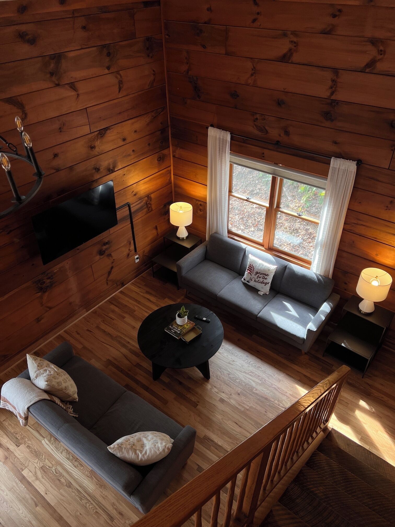 L’intérieur d’une cabane en rondins, avec un ensemble de canapés, une table basse, un téléviseur et une fenêtre avec des rideaux.