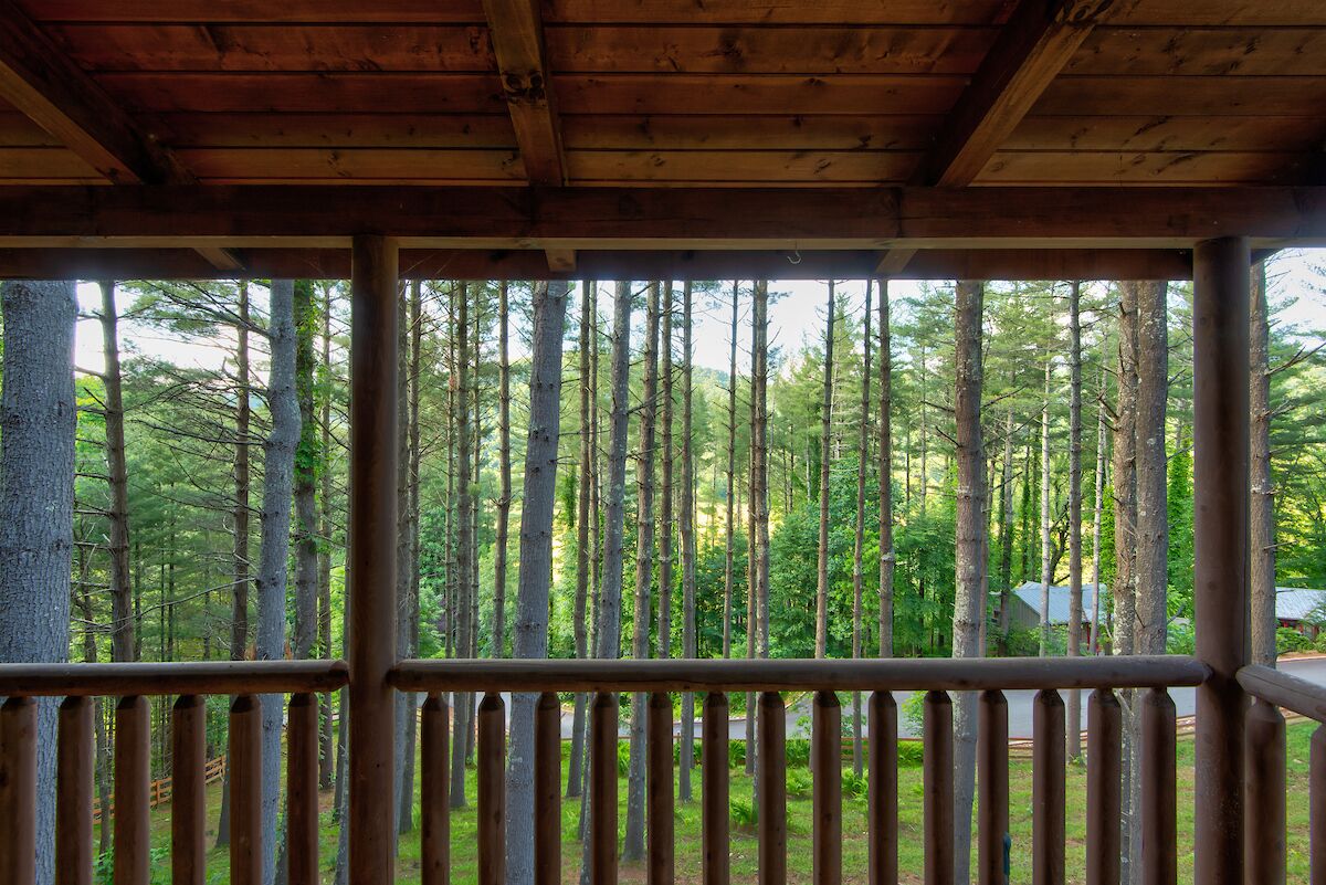 A wooden cabin with a balcony overlooking a forest.