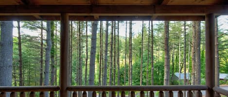 A wooden cabin with a balcony overlooking a forest.
