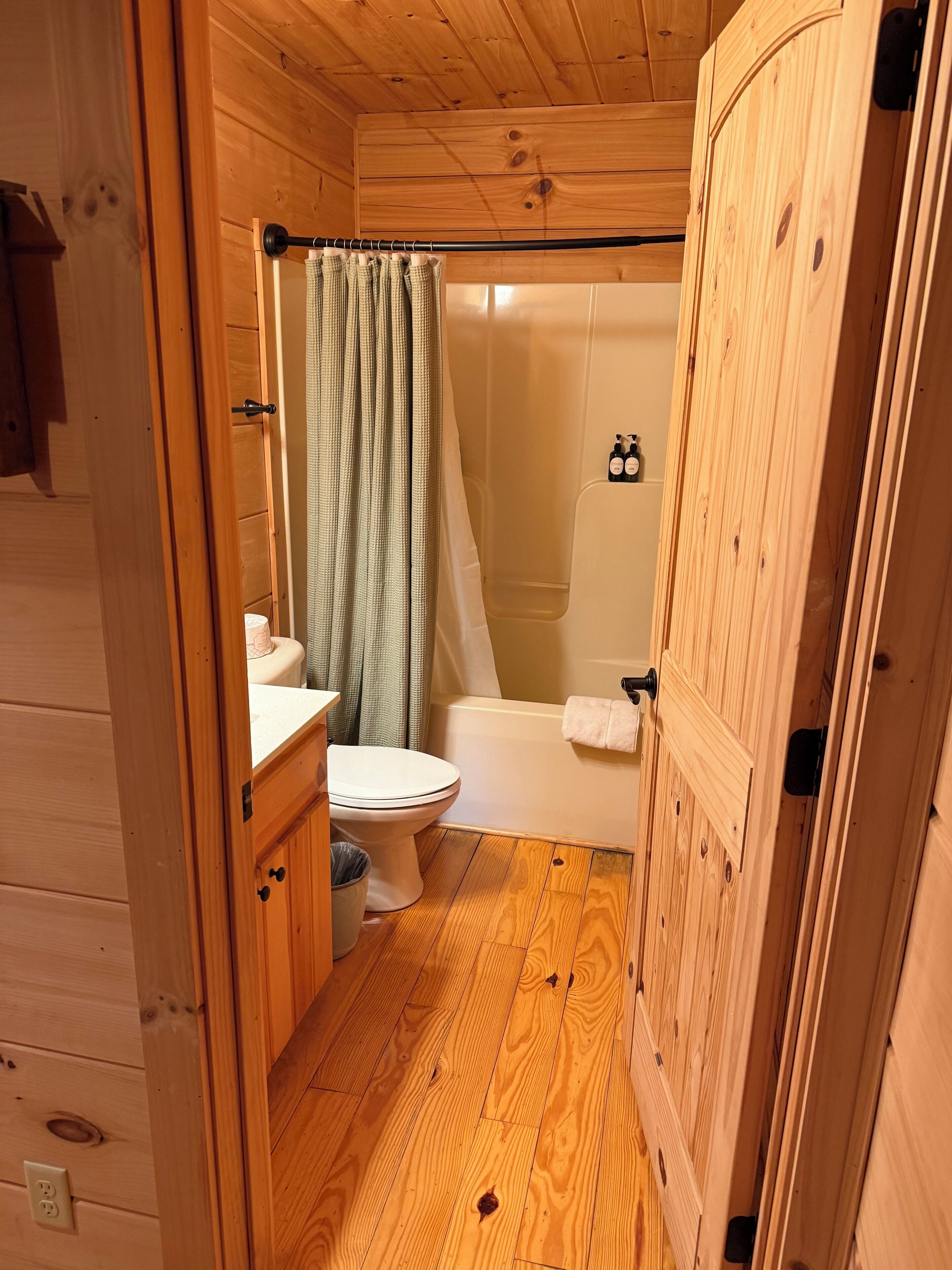 Baño de una cabaña de madera con inodoro, lavabo y ducha.