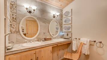 A bathroom with two sinks, wooden cabinets, a large mirror, and a towel rack.
