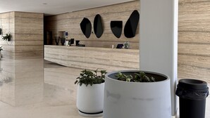 Una moderna zona de recepción con suelo de mármol, plantas en macetas y un mostrador de atención.