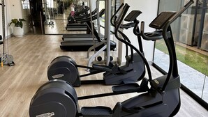 Un gimnasio con múltiples cintas de correr y máquinas elípticas, suelo de madera y ventanas amplias.