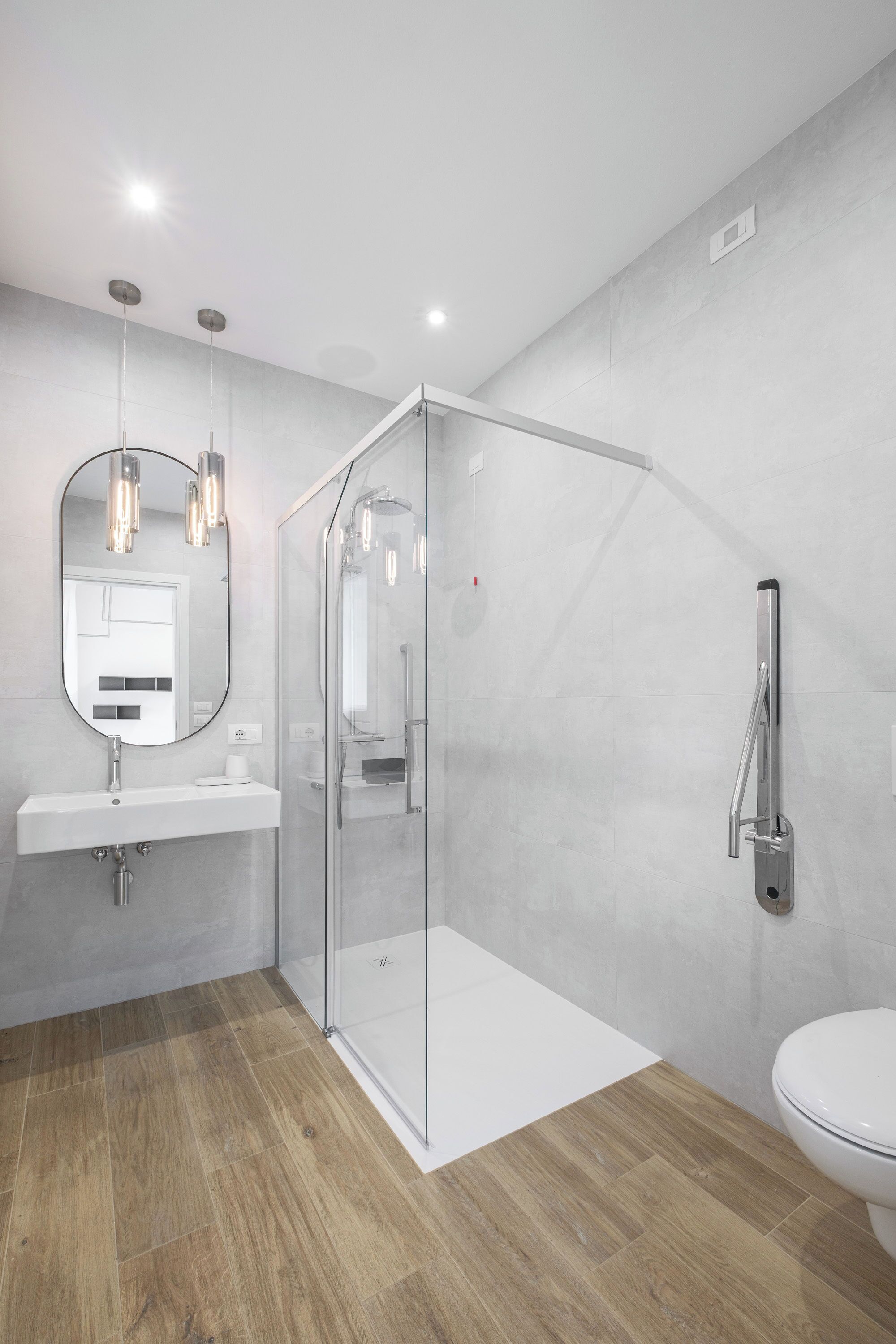 Un baño moderno con cabina de ducha de vidrio, un lavabo con espejo y un inodoro.