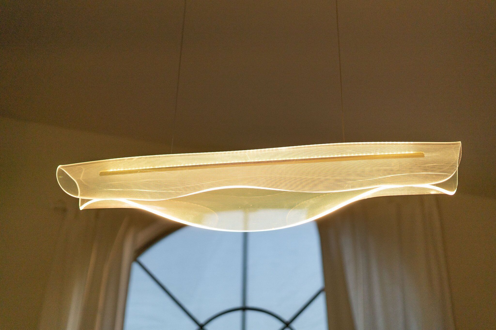 A modern ceiling light fixture with a unique, flowing design.