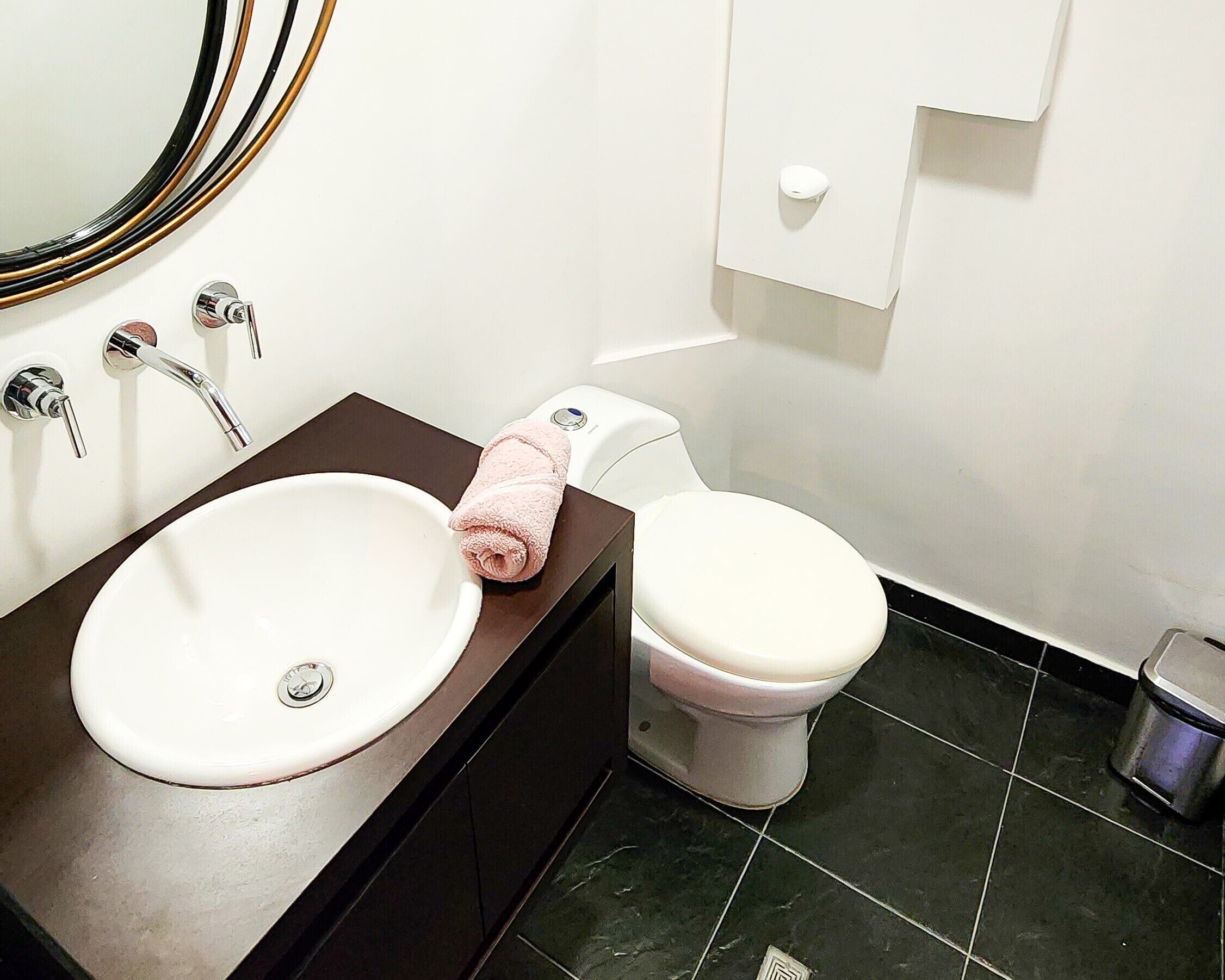 A bathroom with a white sink, a toilet, and a towel on the sink.