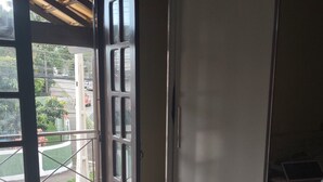 A room with a sliding door leading to an outdoor area, tiled floor, and a visible trash bin. - Casa de Família Próx a Praia do Centro (Rio das Ostras)