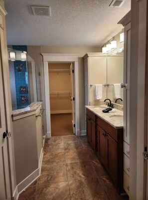 A narrow hallway with a bathroom on the right, featuring a sink and mirror.