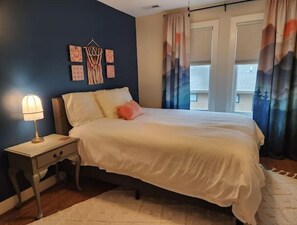 A bedroom with a bed, nightstand, and wall art.