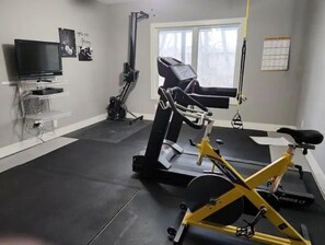 A home gym with exercise equipment including a treadmill, stationary bike, and rowing machine.