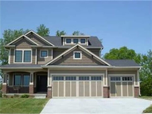 A two-story house with a garage, a front porch, and a driveway.