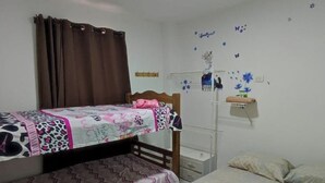 A dormitory room with two bunk beds, a desk, and a wall decoration.
