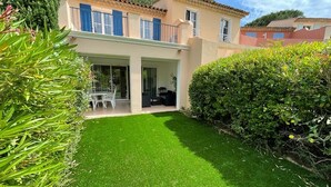 Une maison à deux étages dotée d’un balcon, d’une terrasse avec des meubles d’extérieur et d’une pelouse bien entretenue.