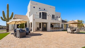 A modern two-story house with a patio area featuring outdoor furniture and umbrellas. - 1+ Acre 5 Bedroom Desert Oasis with Pool and Mountain Views! (Apache Junction)